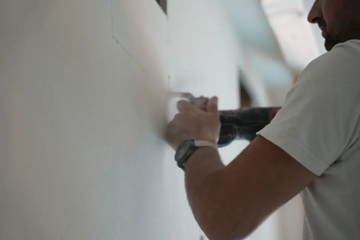 DIY home improvement: a person using a power tool on a wall project.