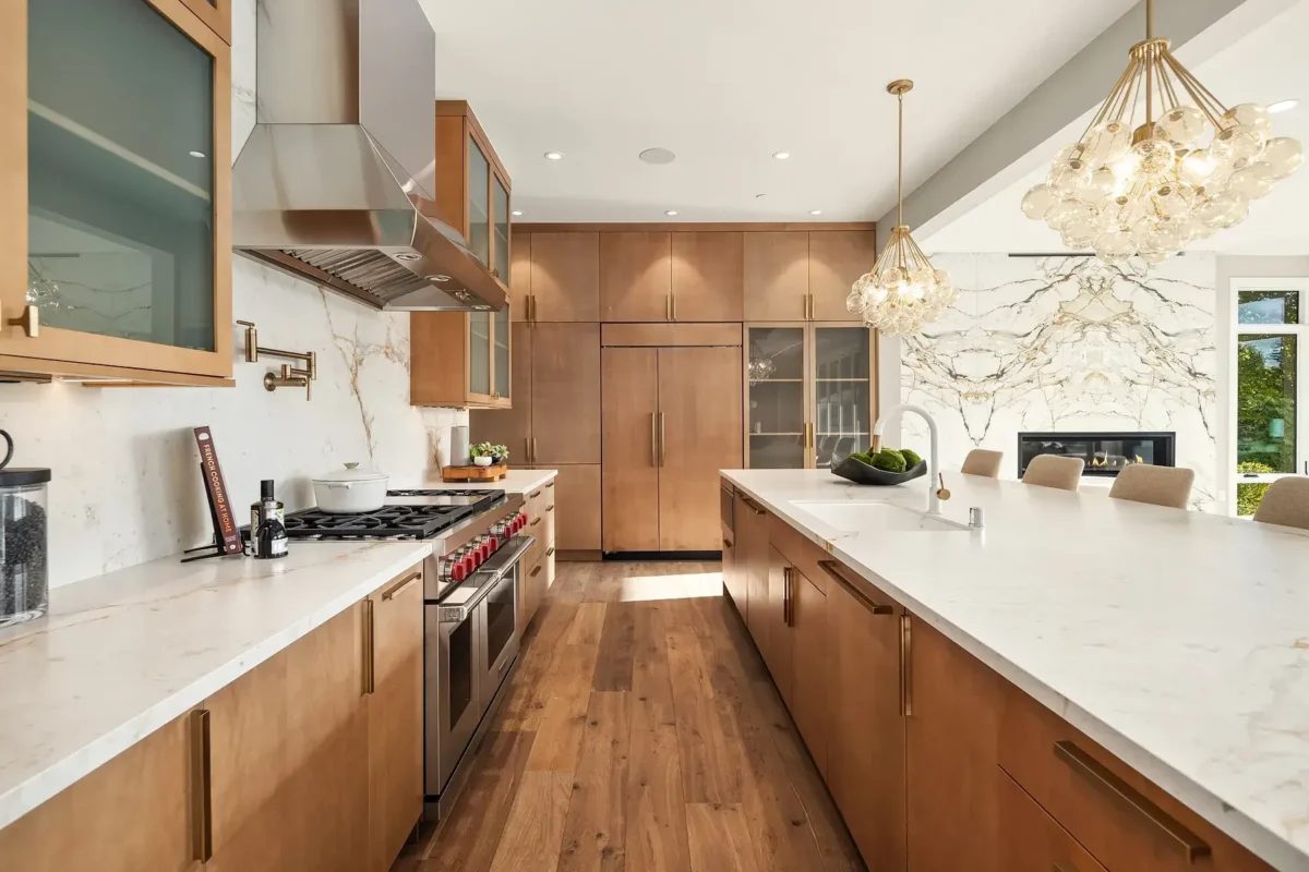 Elegant modern kitchen with warm wood accents, white marble countertops, and stylish lighting.