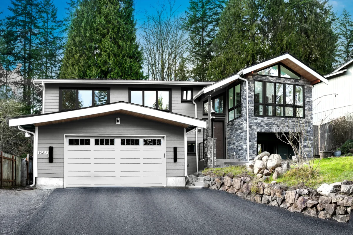 Contemporary home surrounded by lush greenery and tall evergreens in a tranquil setting.