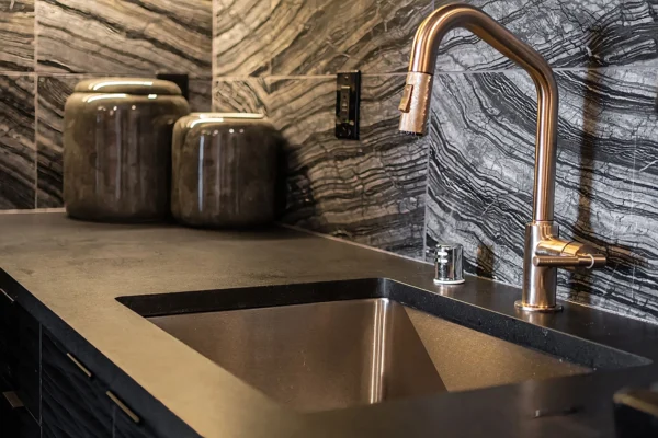 Sleek modern kitchen design featuring curved countertop, stainless steel sink, and rose gold faucet.