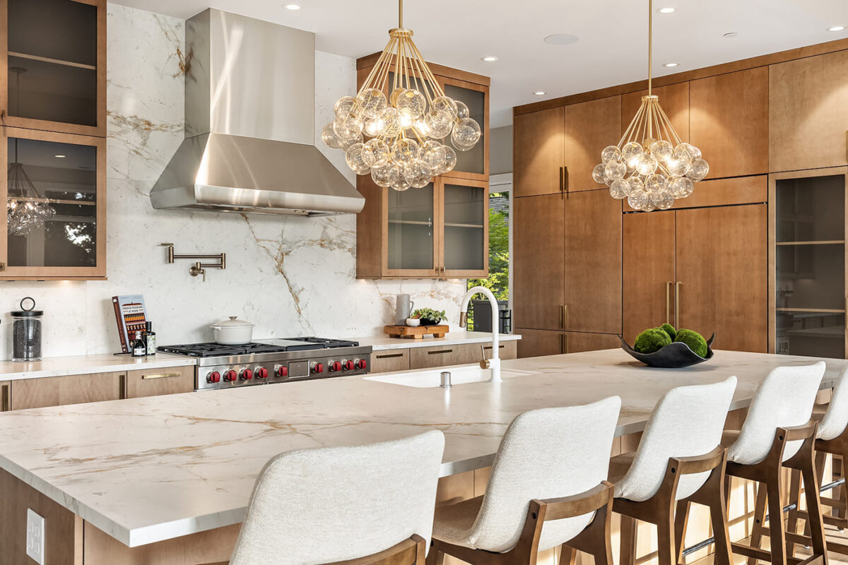 Elegant modern kitchen design featuring a marble island, plush bar stools, and upscale cabinetry.