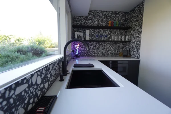 Contemporary kitchen with white countertop, patterned wall, and modern decor inviting social gatherings.