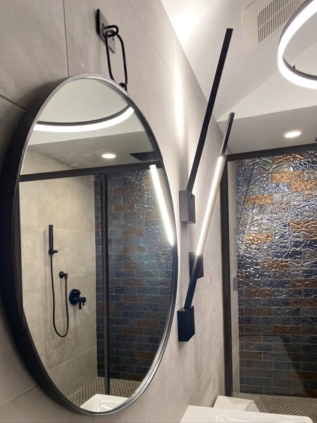 Sleek modern bathroom design featuring a stylish oval mirror, innovative LED lighting, and textured shower tiles.