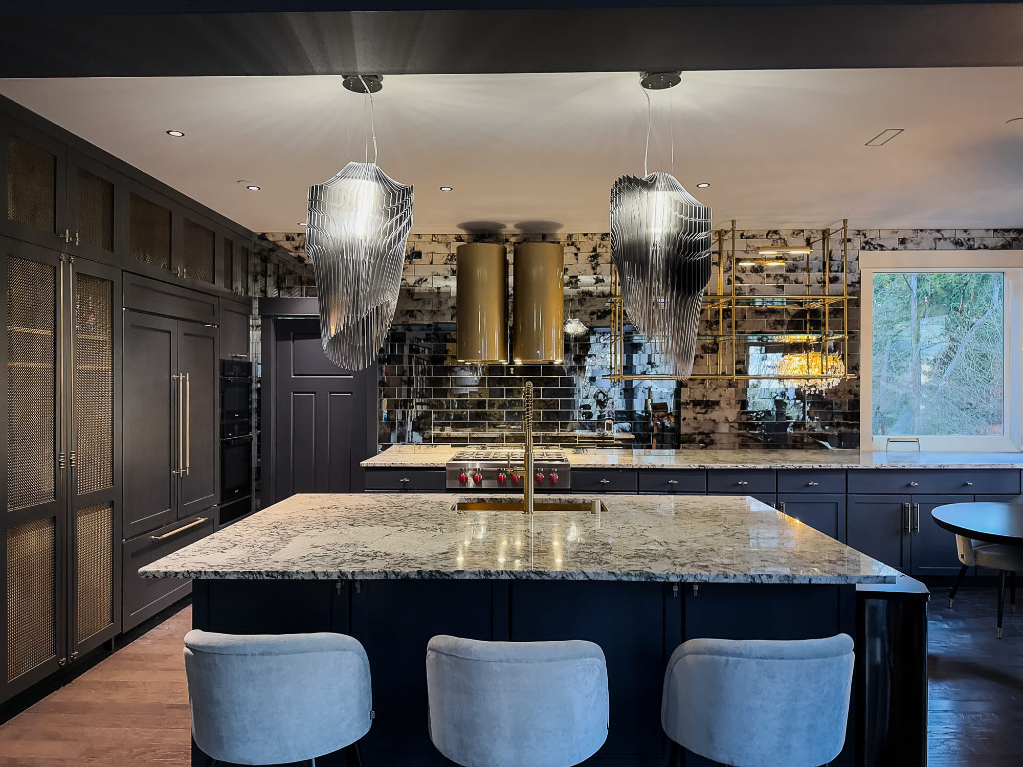 Luxurious modern kitchen with dark cabinetry, marbled countertops, and striking pendant lights.