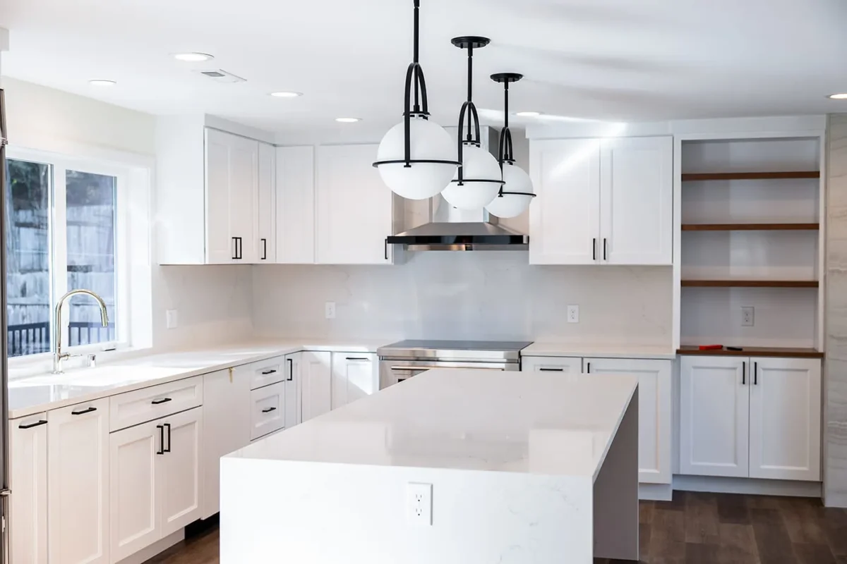 Modern white kitchen designed by Medina design build firm with white cabinetry, quartz island countertop, black pendant lights, stainless steel appliances - design build services Medina by ARIID Build & Remodel